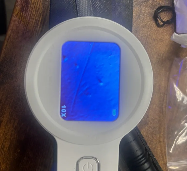 A second view through the kit's digital microscope at 10x, showing a few particles on the filter membrane