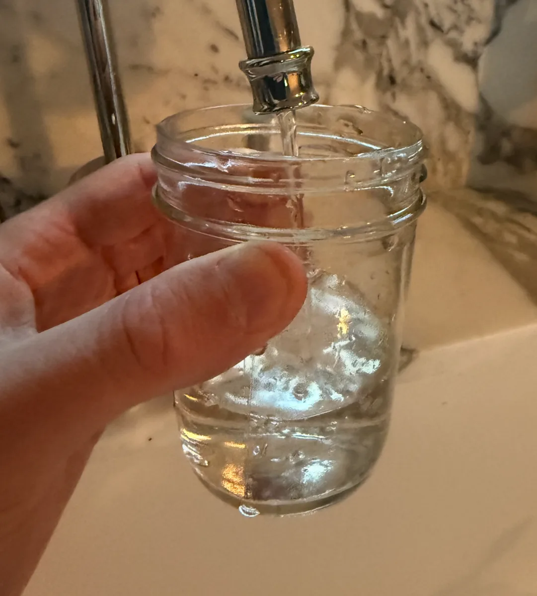 Filling a clean glass jar with tap water