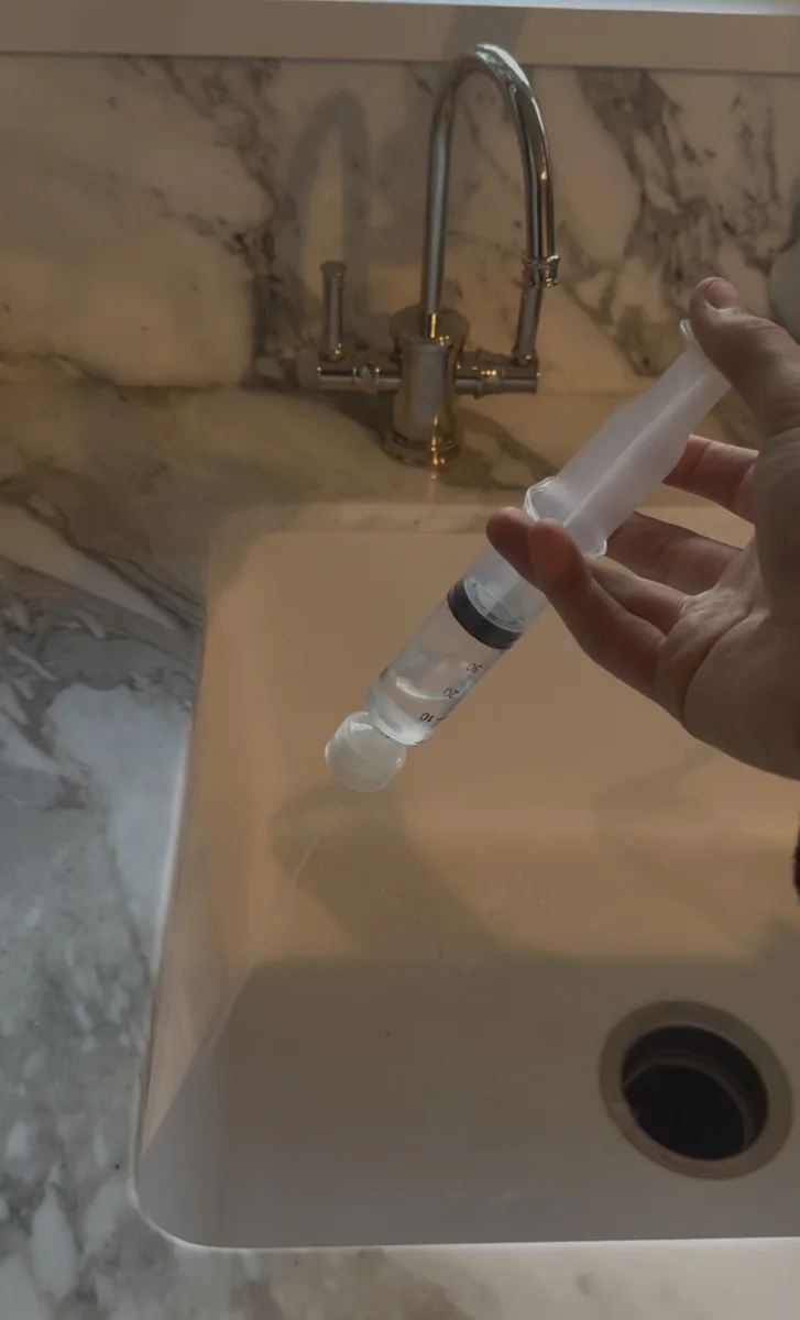 Pushing a water sample through the syringe filter over a sink