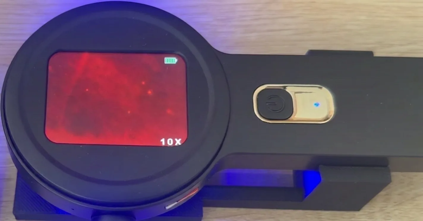 Microscope view with microplastic particles — faint glowing dots on the red field (example 2)