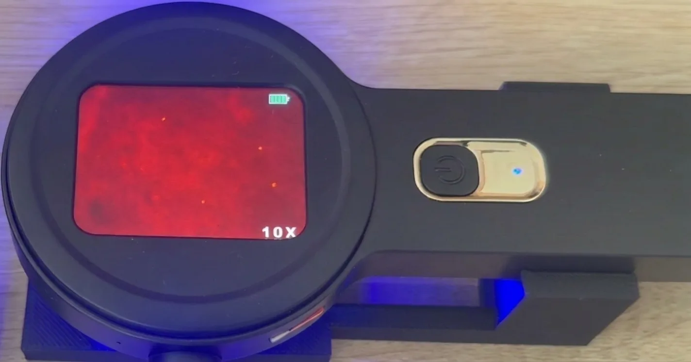 Microscope view with microplastic particles — faint glowing dots on the red field (example 5)