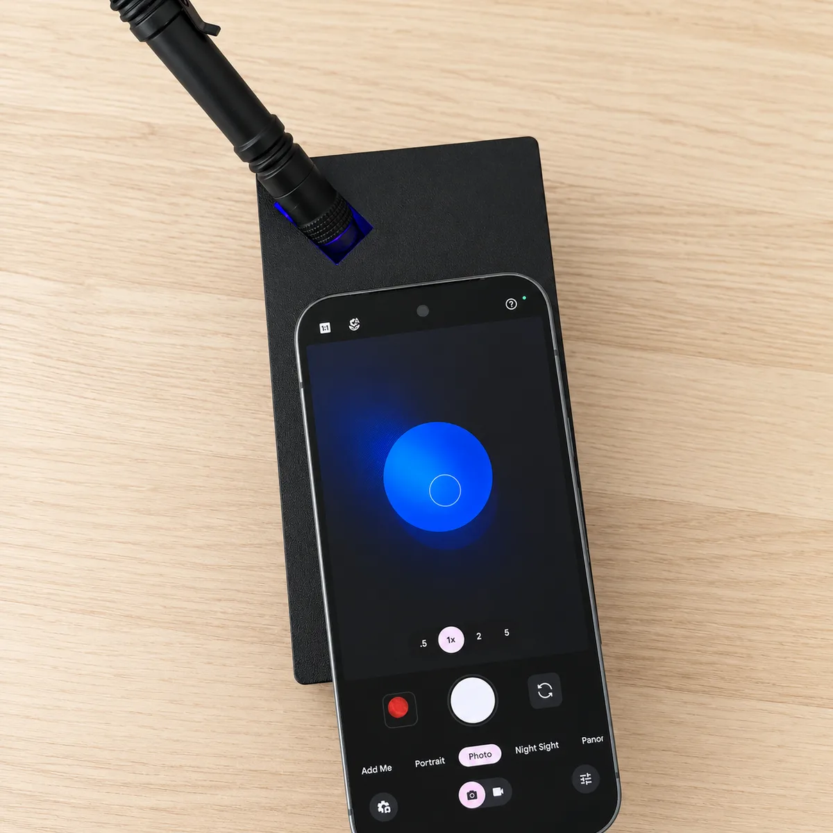 A phone resting on top of the imaging box with its camera app open, showing the glowing filter