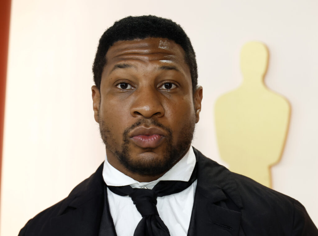 Jonathan Majors faces the camera in a black tie.