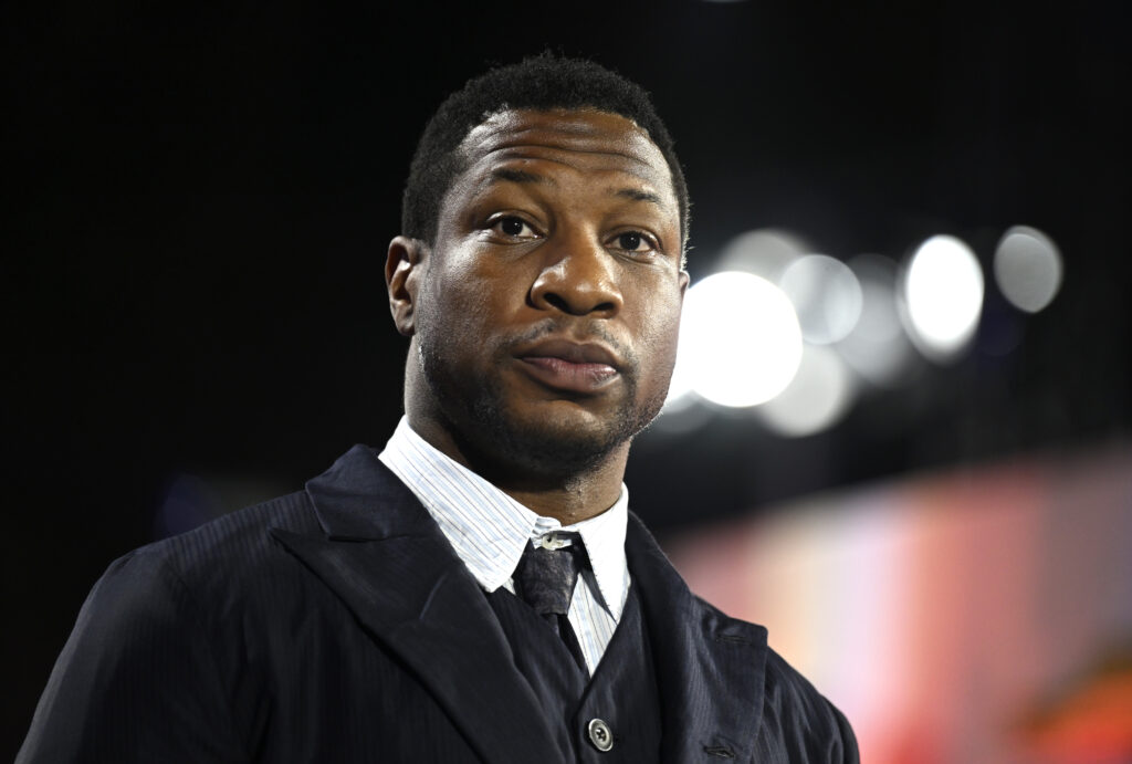 Jonathan Majors wears a serious expression at an event.