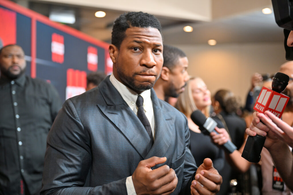 Jonathan Majors makes an unclear expression while at a public event.