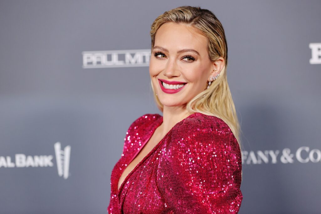 Hilary Duff smiles while wearing a gorgeous raspberry top.