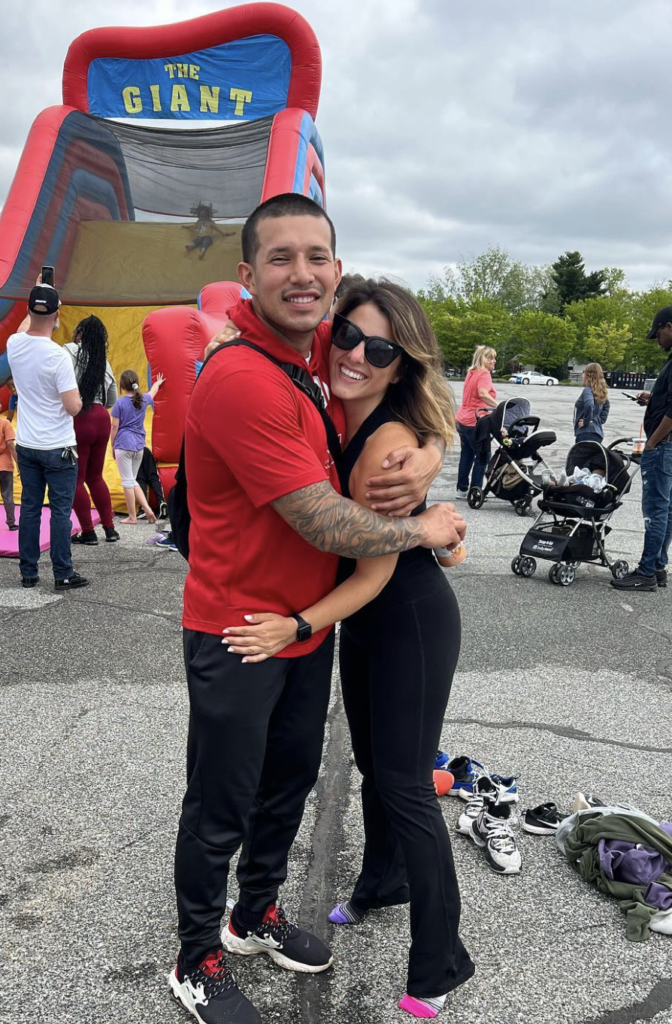Javi Marroquin and Lauren Comeau embrace at an outdoor carnival.
