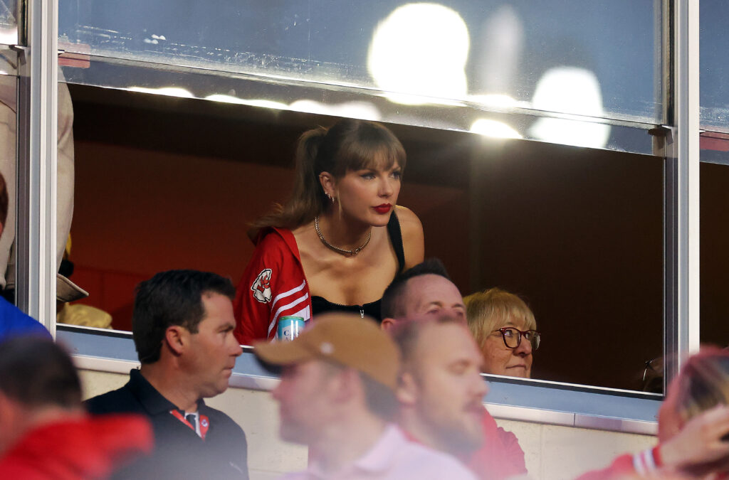 Taylor Swift peers through the window of her stadium box.