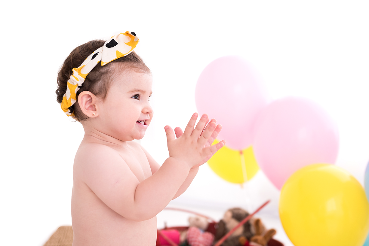 bebê fofa com laço na cabeça e festa temática com balões coloridos