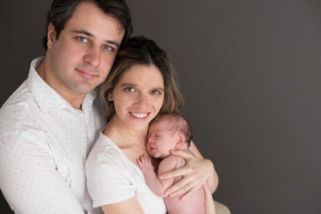 foto de recém-nascida com pai e mãe em estúdio fotográfico na zona oesta de são paulo fundo cinza quais as poses para fotos newborn