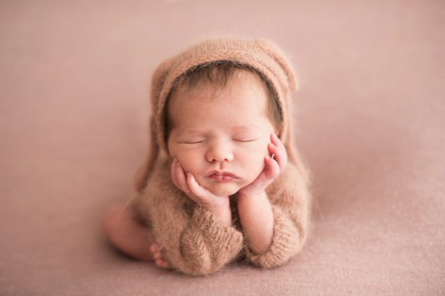 bebê fofo com as mãos no queixo com touca bege estúdio de fotografia newborn como fazer o atendimento aos clientes