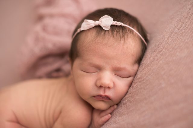 ensaio de fotos com bebê recém-nascido com tiara no cabelo e de olhos fechados em estúdio de fotografia newborn laura alzueta na zona oeste de são paulo