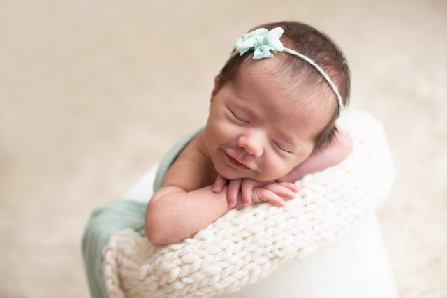 ensaio de fotos com bebê recém-nascido com tiara no cabelo e de olhos fechados em estúdio de fotografia newborn laura alzueta na zona oeste de são paulo