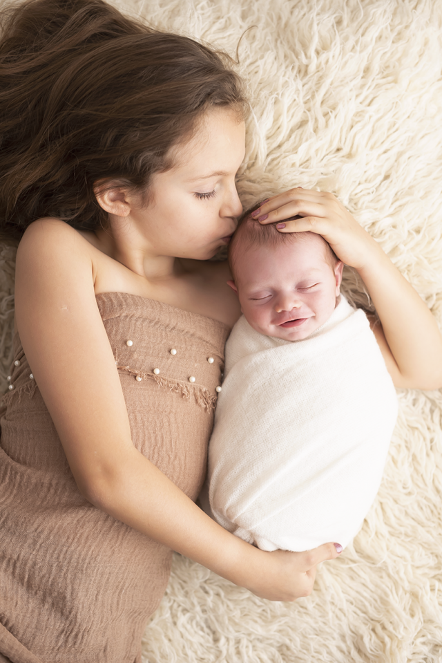 caretas de recém-nascidos fotos de bebê sorrindo com irmã mais velha fundo com cores nude em estúdio fotográfico em pinheiros são paulo laura alzueta