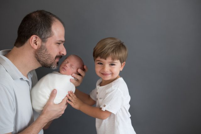 ensaio newborn com irmãos foto de menino de 3 anos com recém nascido e pai em estúdio fotográfico em pinheiros SP
