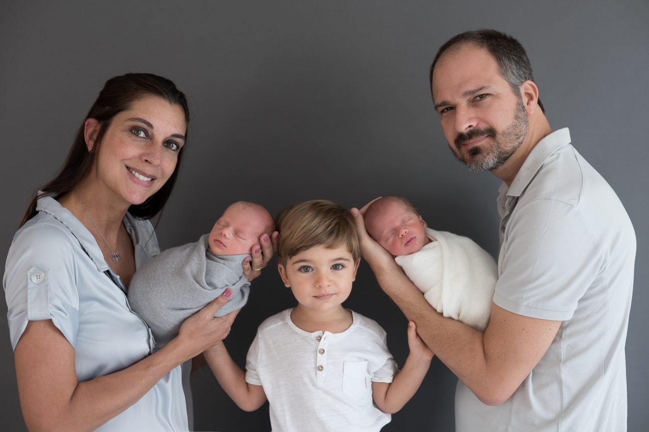 família posando em estúdio de fotografia newborn em ensaio de gêmeos com irmão mais velho