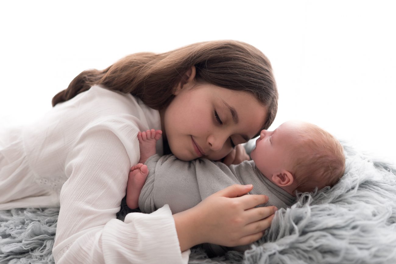 ensaio newborn com irmãos menina abraça com carinho irmão recém nascido foto por laura alzueta