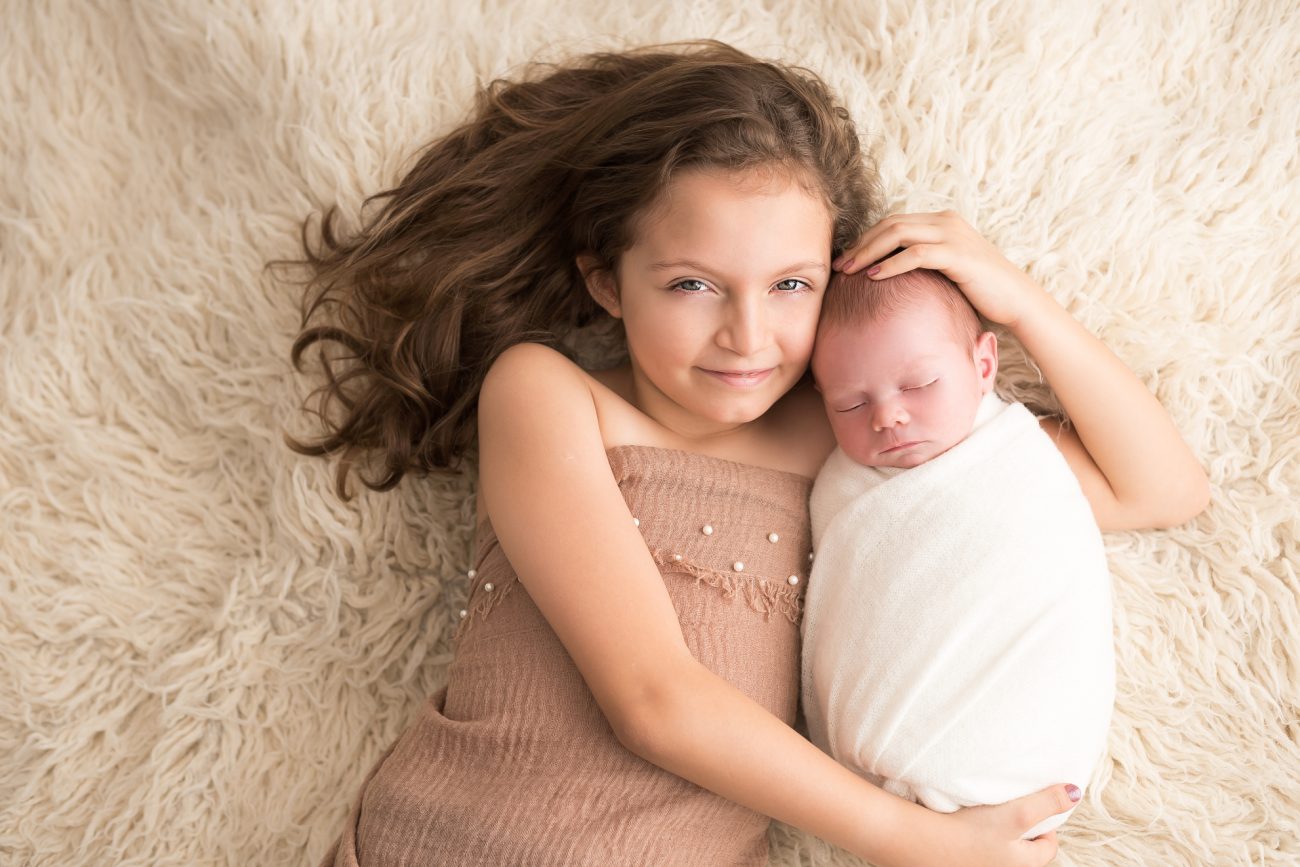 ensaio newborn com irmãos menina mais velha com bebê recem nascido em fotos do estúdio fotografico laura alzueta