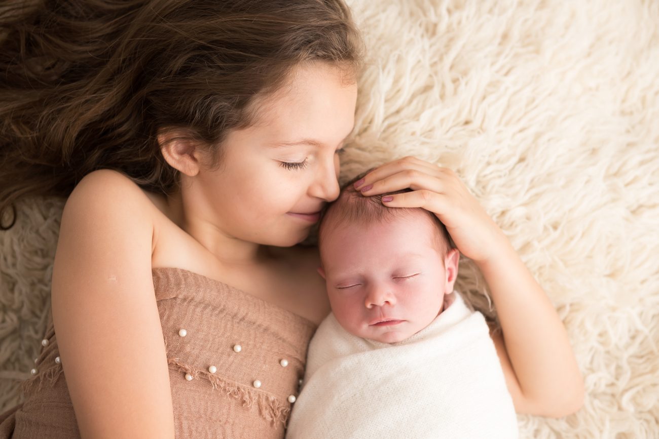 ensaio newborn com irmãos menina mais velha com bebê recem nascido em fotos do estúdio fotografico laura alzueta