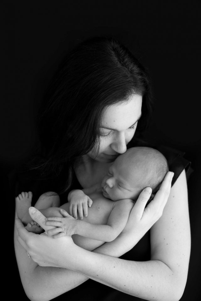 mãe segurando bebê com fundo preto em estúdio fotográfico fotos de ensaio newborn de menino composição fotografia laura alzueta são paulo