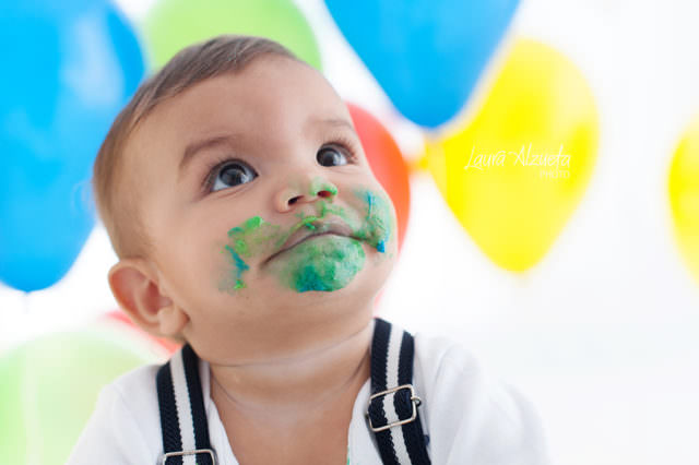 festa com balões coloridos em fotos de estúdio menino sujo de bolo em ensaio Smash the Cake em fotos de aniversário de bebê estúdio fotográfico laura alzueta