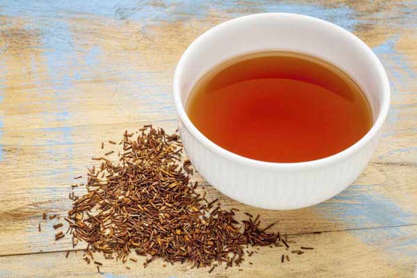 rooibos red bush tea - a white cup of a hot drink and loose leaves