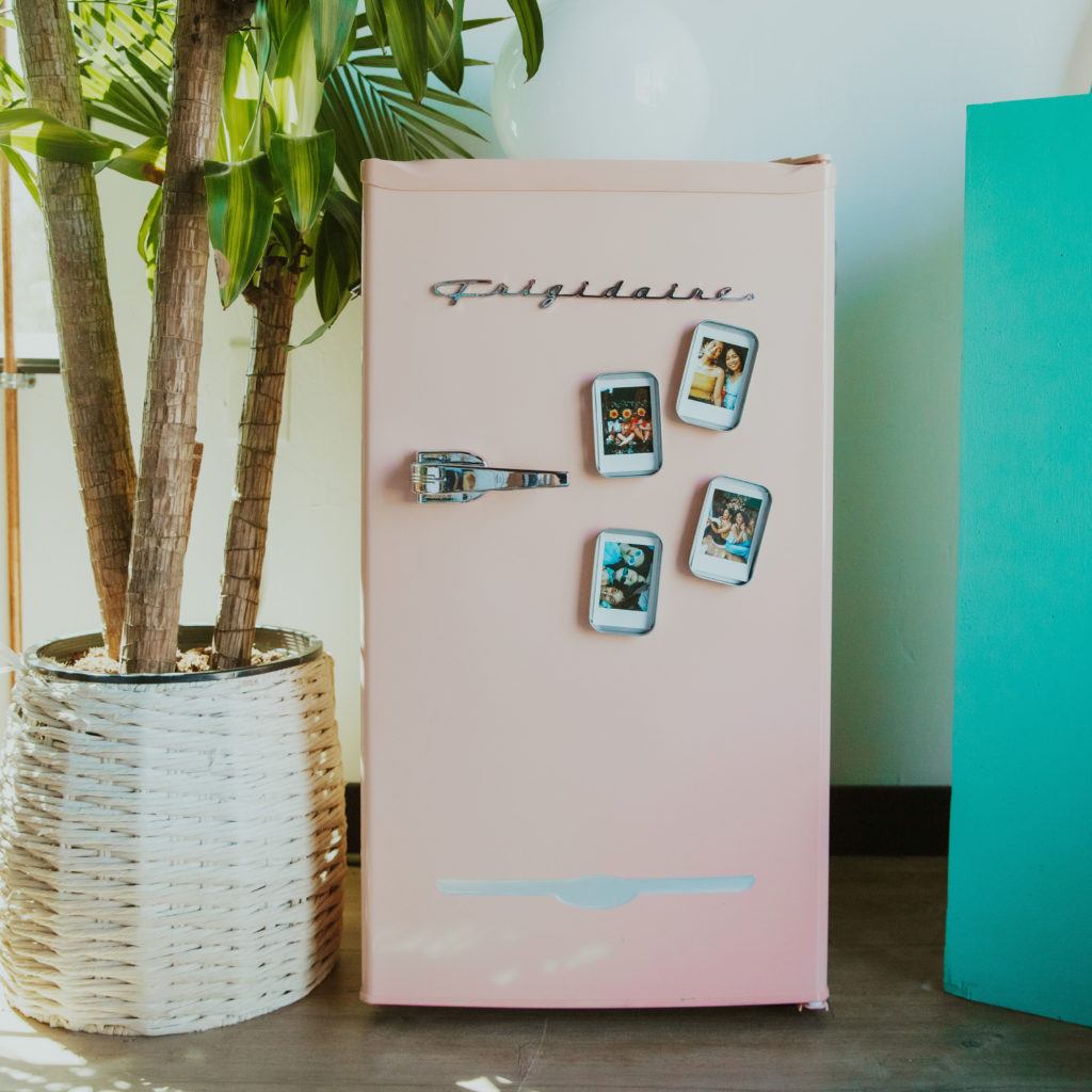 mini geladeira com várias fotos dentro de porta retratos de caixinhas coladas em sua porta