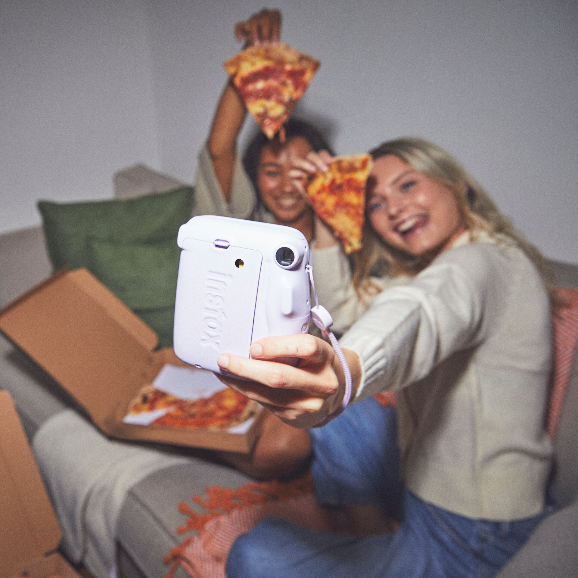duas meninas comendo pizza e tirando fotos com câmera Instax Mini 11