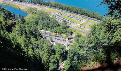 An eastbound UP autorack/intermodal train is framed by the trees, as it makes its way down the Columbia River Valley. Seen from the top of Multnomah Falls, Oregon.