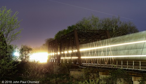 I like night shots of passing trains less for the laser light show and more for the  way the headlights sometimes illuminate the surrounding scenery beautifully. In this case, it's an eastbound NS intermodal train lighting up the blooming trees, as it crosses the Raritan River, in Bridgewater, NJ, on an early day in May.