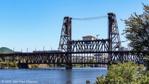 "GO PANTHERS!" is displayed on the side of the MAX Light Rail Car as it crosses the Steel Bridge over the Willamette River, in Portland, Oregon. The bridge is a double decker that carries the MAX and cars, on top, and the, "real", trains on the bottom.