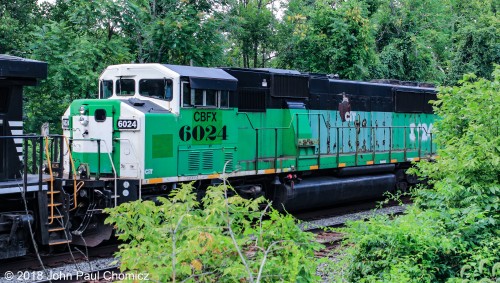 CBFX #: 6024, still in its ex-BN Grinstein Green paint, peaks out from the bushes as it is second of three units on an eastbound autorack train, in Glendon, PA.