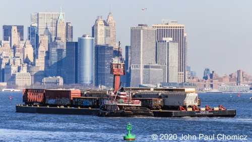 In a scene reminiscent of the era when it was a requirement for all New York area railroads to have a harbor fleet, the Marjorie B. McAllister chugs along New York Bay with a railroad float barge near Bayonne, NJ with the skyline of downtown New York as a backdrop. It is headed for interchange with the New York New Jersey Railroad at Greenville Yard, in Jersey City, NJ. The New York New Jersey Railroad is the last remaining float operation in New York Harbor, which ferries rail cars between Greenville Yard in Jersey City, NJ and the 65th Street Rail Yard in Brooklyn, NY. It provides a direct rail link from Long Island to the main railroad terminals in New Jersey and avoids a lengthy detour from the north, via Selkirk.