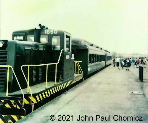 Forgive the bad quality and angle but it is too interesting not to share. This is a photo of the U.S. military GE 80-tonner centercab unit #: 1650. This was one of two centercab units that provided the switching services for the former Military Ocean Terminal Bayonne Yard (MOTBY) in Bayonne, NJ. This photograph was taken by me, with a Polaroid camera, on one of the Armed Forces Day sometime between in 91 and 93. During the Gulf War, there was a heightened sense of patriotism and appreciation for our armed forces, so the MOTBY opened its gates up to the public. These days were extremely fun as there were multiple displays, demonstrations, and events involving the military and emergency services. Due to the size of the base, the #:1650 was paired with two vintage coaches, of unknown origin, and provided shuttle services between the different areas of the base. Good times but I wish I was a bit better with my photography when I was nine years old.