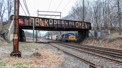 A short, CSX mixed freight train passes under the NS Morrisville Yard access track, on a dismal, dark afternoon in Woodbourne, PA.