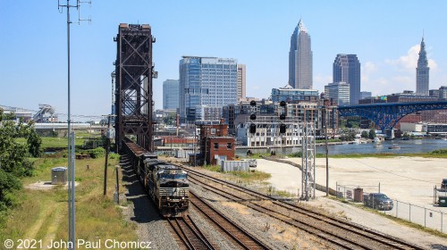 With the lightning not quite right, just yet, a westbound empty hopper train leaves downtown Cleveland behind, as it crosses the drawbridge over the Cuyahoga River. A slightly different angle to get an unobstructed view of Drawbridge Tower.