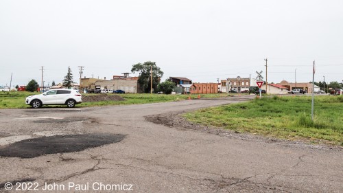 As the young Indiana Jones runs across the railroad and nears the camera, the camera pans out to show more of the town in the background. This photograph shows that not much has changed in Antonito since the 1910's when he was a child. The only difference seems to be the modern cars parked in the background rather than the vintage cars that were apparent in that scene.