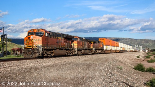 A westbound BNSF intermodal train passes by the flag plaza of the Vietnam War Memorial in Grants, NM.