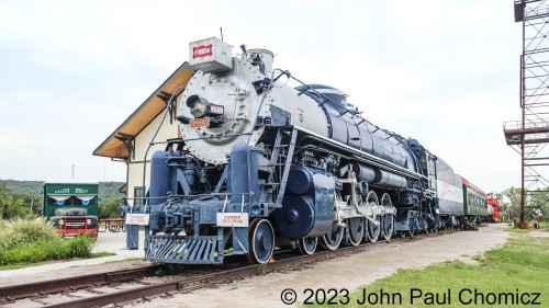 The Frisco #: 4500 from the opposite side showing that it is among other railroad equipment and vintage vehicles at the Historic Route 66 Village in Tulsa, OK. The Red Fork Depot, in the background, is not an original station and was built recently as an information center and event hall.