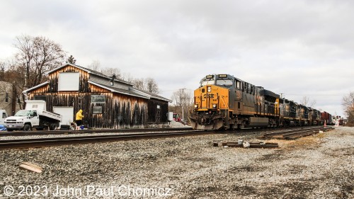 It's all 3's leading an eastbound mixed-freight past what looks like an old wooden freight depot in Voorheesville, NY.