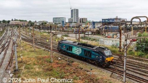 While it does make things quite confusing, the multiple railroads that lease the UK railway makes for an interesting railfanning experience with multiple paint schemes and different power variety. I almost missed this light unit as it headed westbound through Willesden Junction. It is the Direct Rail Services #: 68034; a British Rail Class 68 locomotive. I like the interesting star paint scheme.