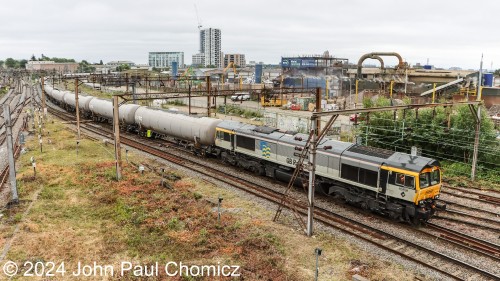 British Rail Class 66 "Steve Hannam" leads an eastbound GB Railfreight unit tank train under the wires at Willesden Junction, London, UK.